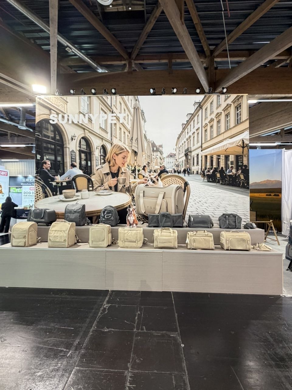 SUNNYPET Interzoo 2026 — khaki eco-friendly recycled pet carrier collection with European cafe lifestyle backdrop